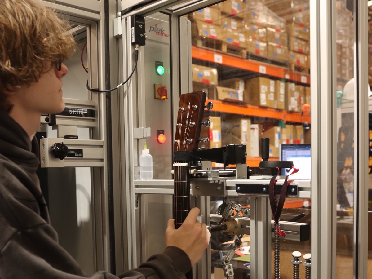 A Corzic technician loading an acoustic guitar into the Plek station